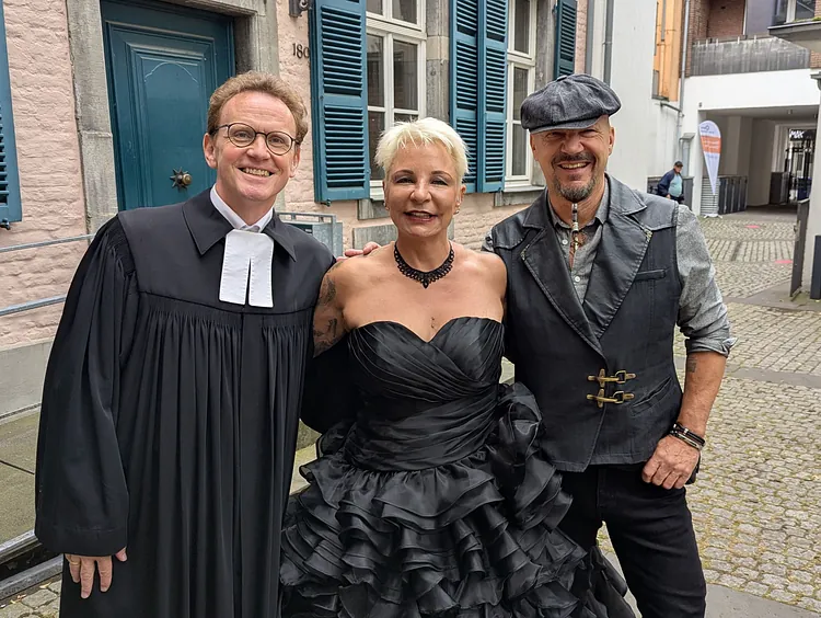 Ganz in schwarz: Pfarrer Peter Krogull, glücklich mit Alina und Uli an der Berger Kirche
