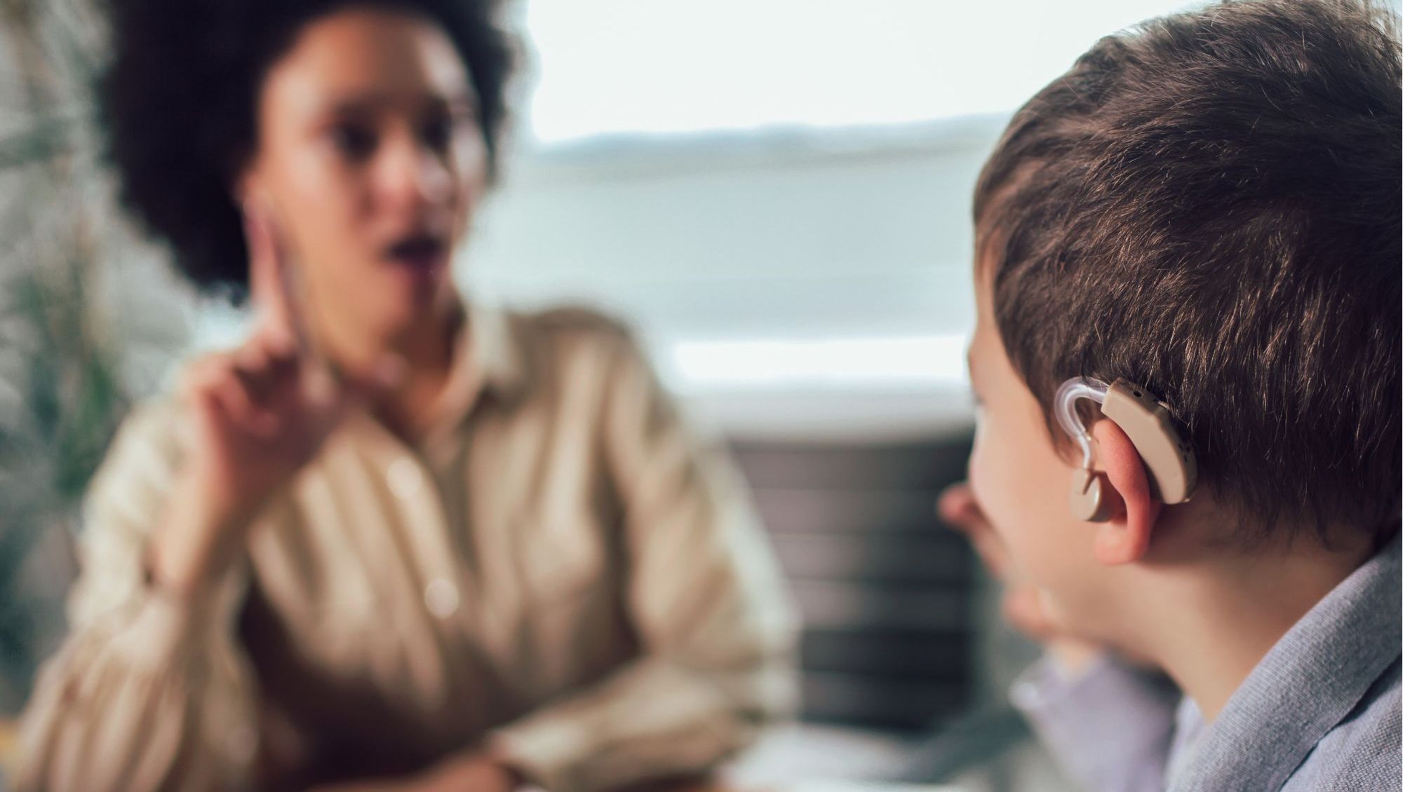 Seelsorgerin für Gehörlose und Schwerhörige im Gespräch mit einem Jungen mit Hörgerät